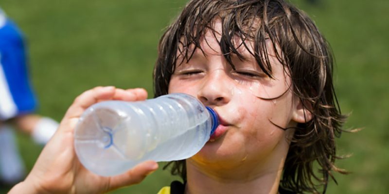Young soccer athlete sweating and drinking water